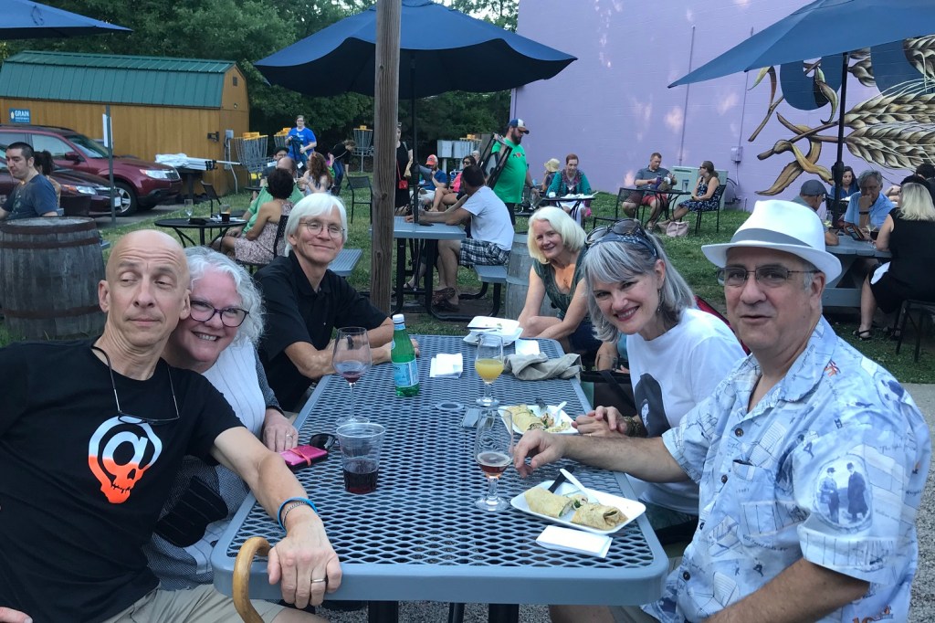 group sitting at picnic table outside, with drinks