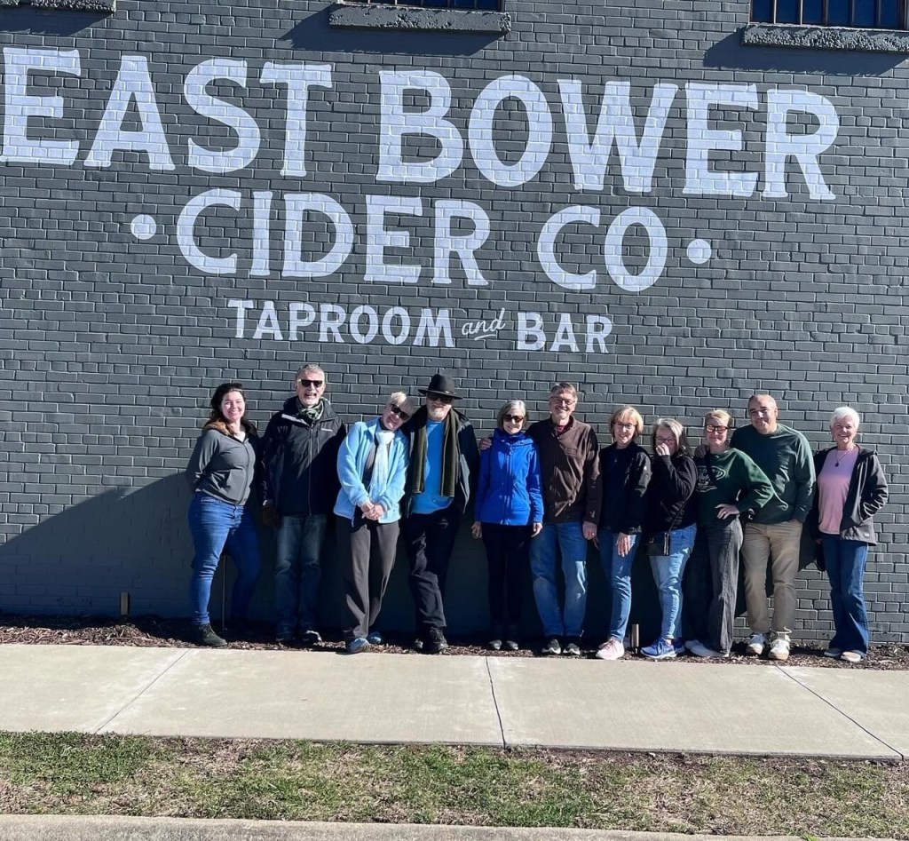 guests stand by the wall with the East Bower Cider Co. sign