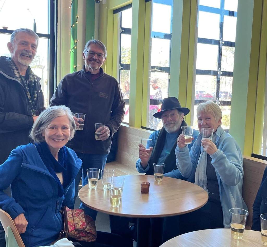 smiling guests sitting around a small table with cider glasses