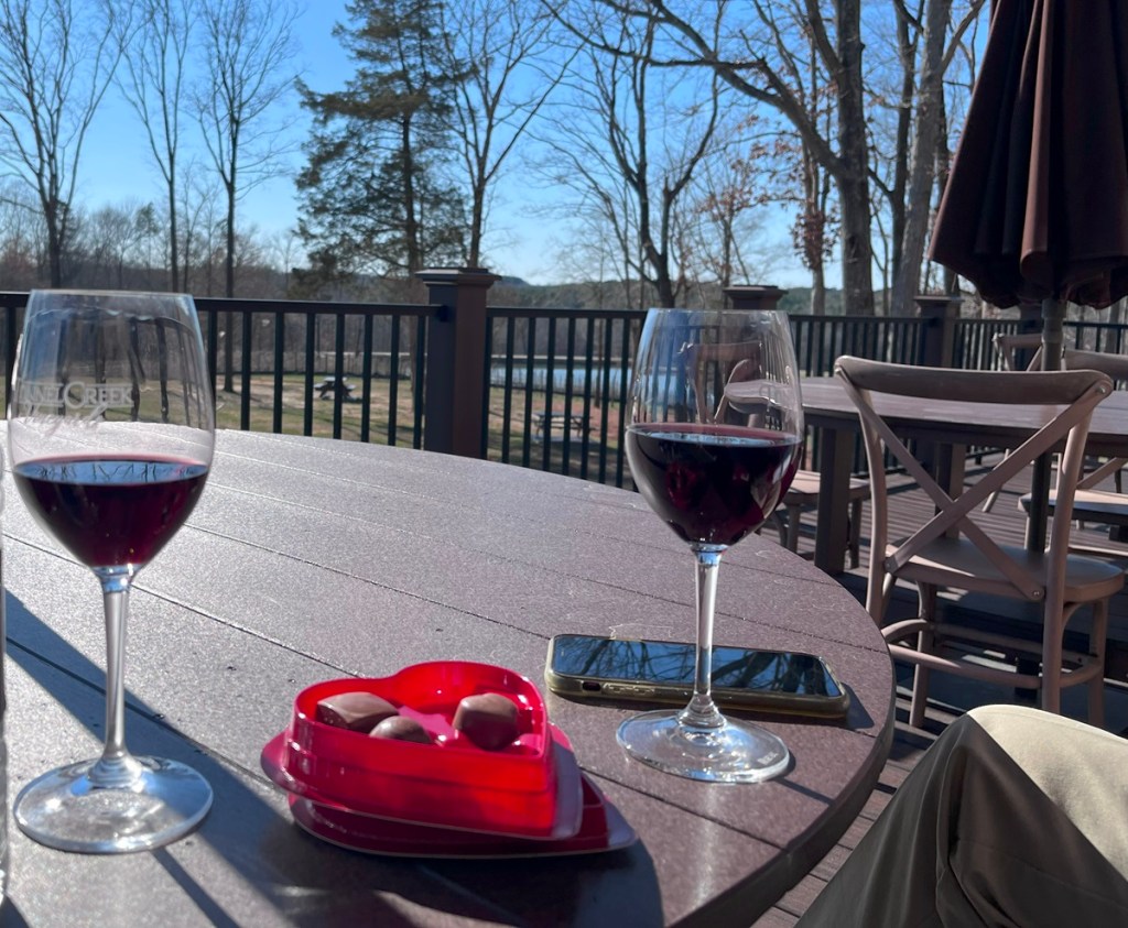 two glasses of red wine sitting on a table outside