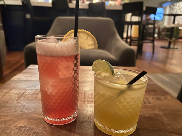 two mocktail glasses, one with pink liquid and lemon, one with green liquid and lime